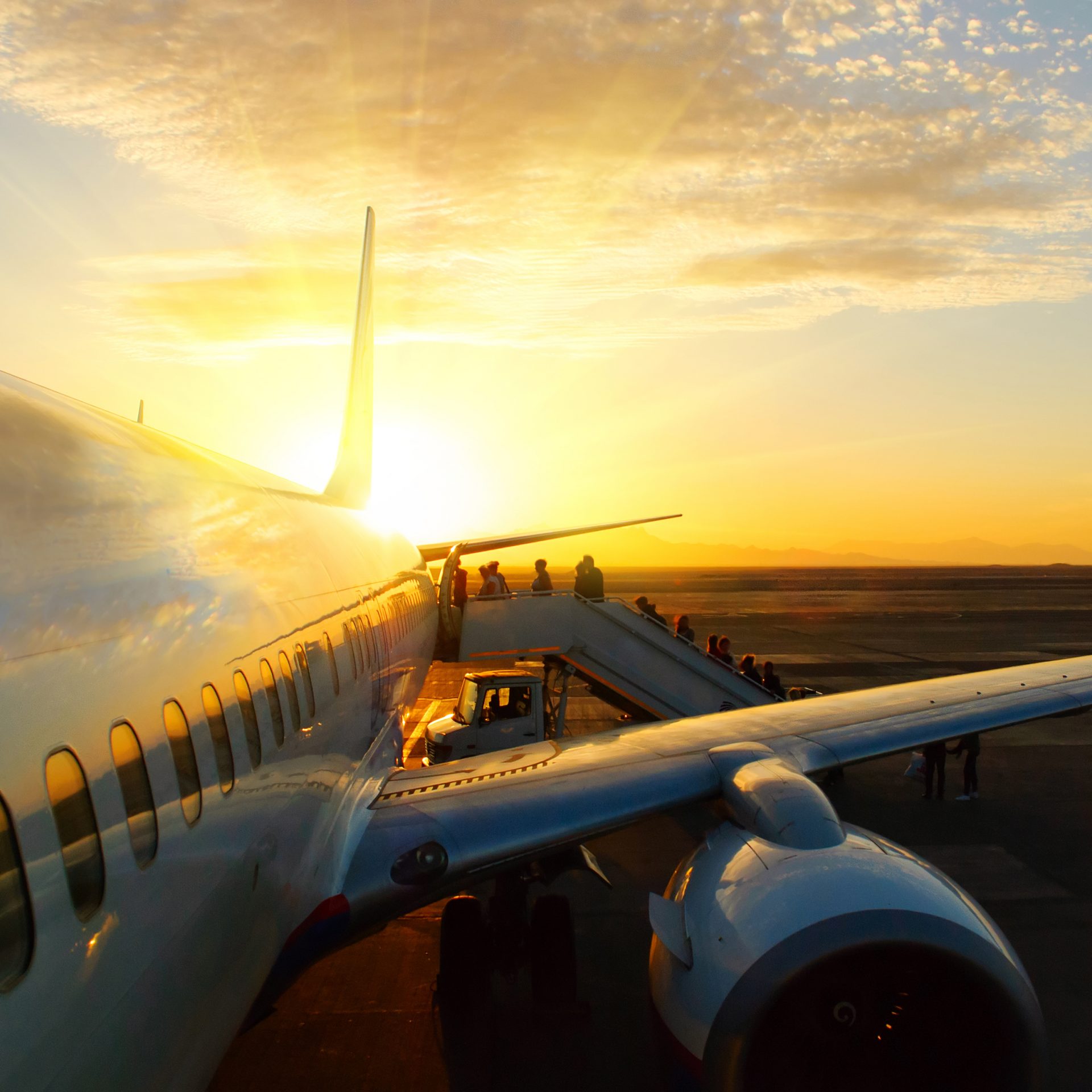 passengers boarding aircraft in airport at sunset